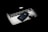 A sleek Apple laptop with its logo glowing subtly is partially covered by an iPhone and a pair of wireless earbuds. The objects are arranged on a dark surface, creating a modern and minimalistic composition with a focus on technology.