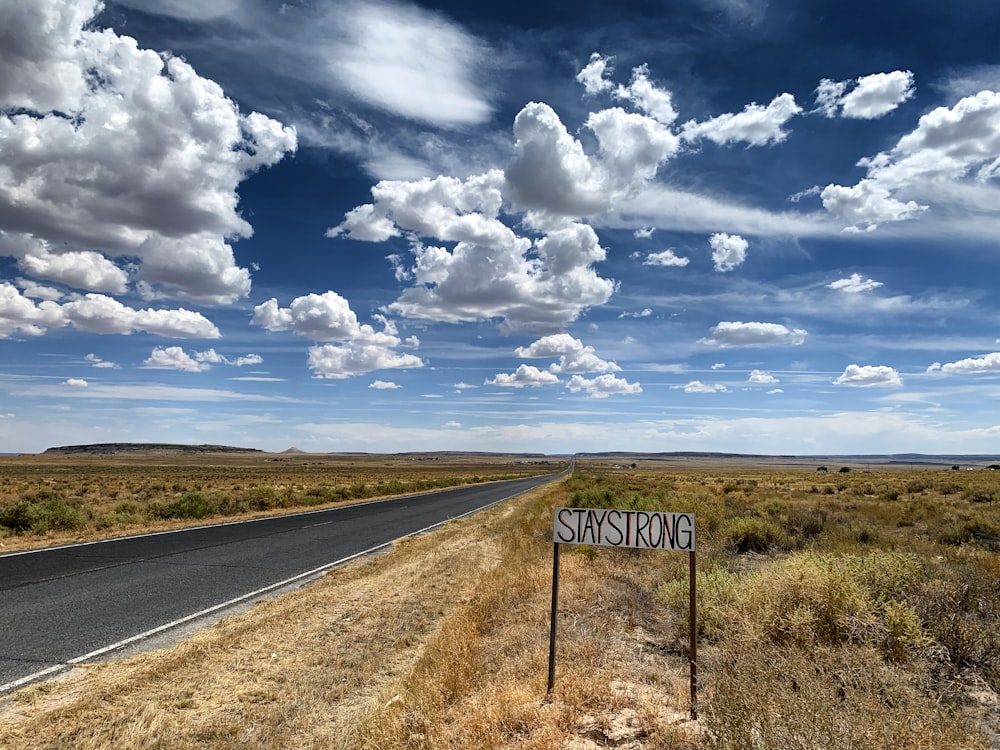 gray asphalt road under blue and white cloudy sky during daytime