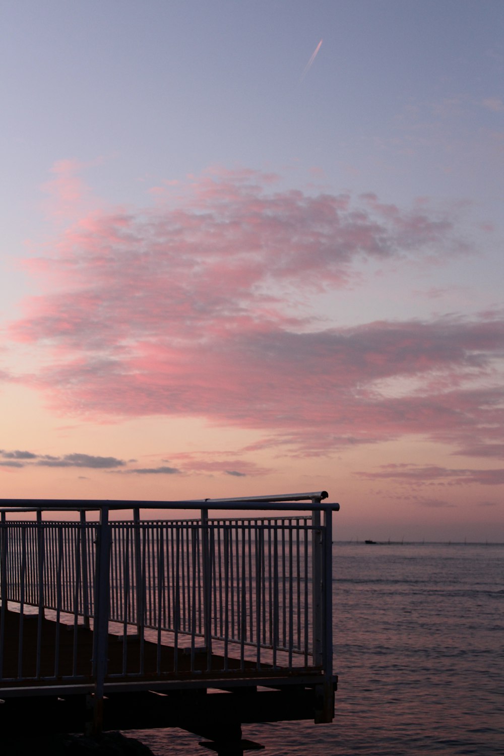 black metal fence near sea during sunset