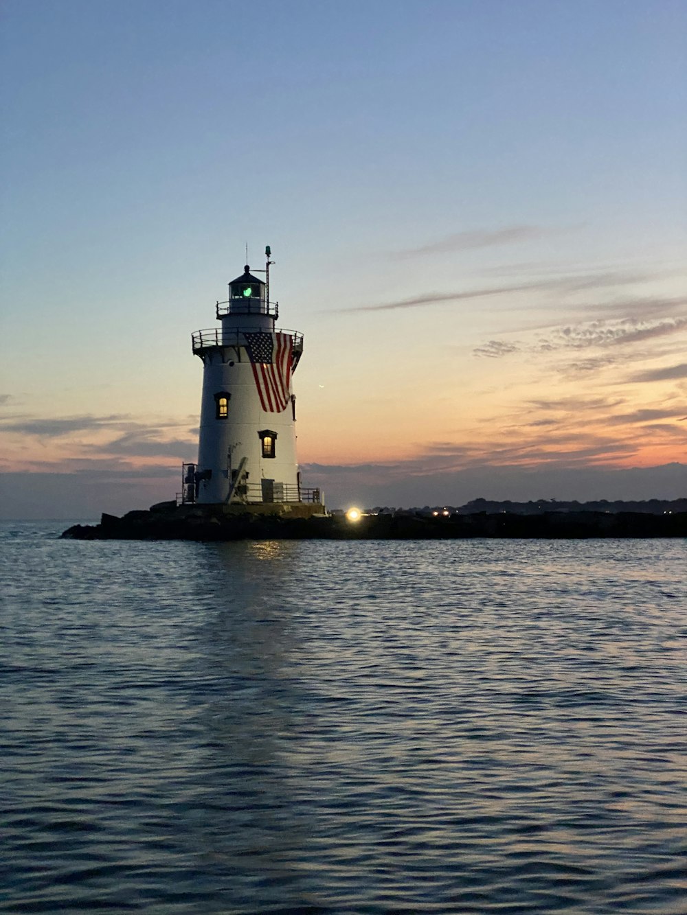 faro bianco vicino allo specchio d'acqua durante il tramonto