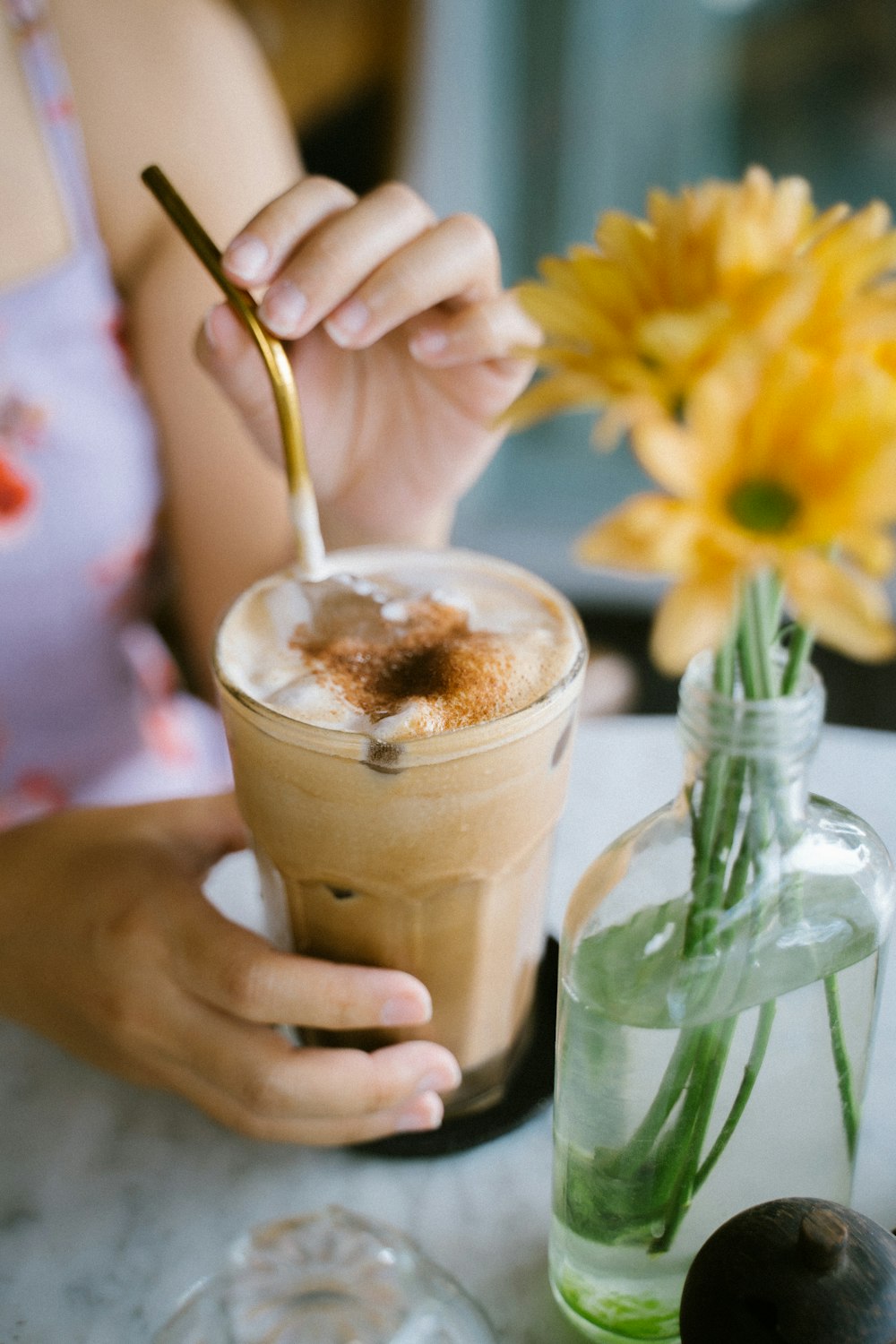 person holding clear drinking glass with brown liquid