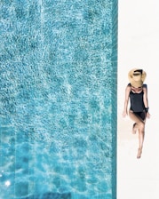 woman in black bikini bottom and white sun hat standing on blue water