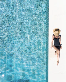 woman in black bikini bottom and white sun hat standing on blue water