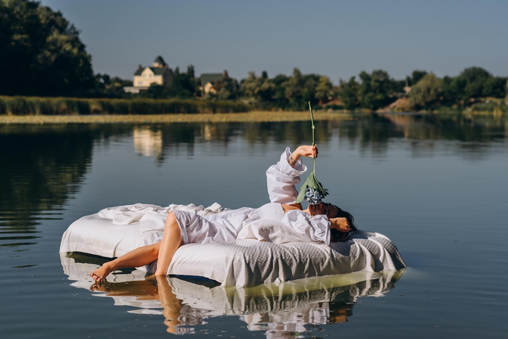 woman in white dress lying on white inflatable boat on lake during daytime