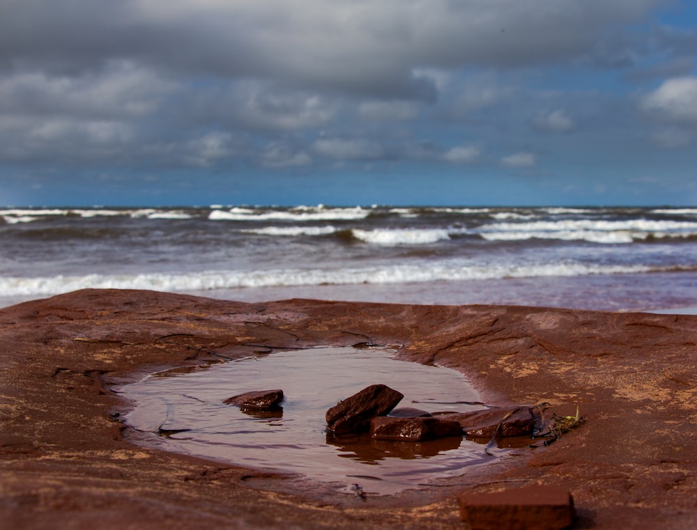 brown rock formation on seashore under white clouds and blue sky during daytime