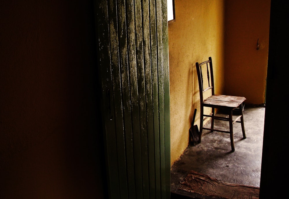 brown wooden armchair beside gray steel wall