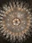 An ornate chandelier with intricate crystal and gold detailing hangs from the ceiling, radiating light. The symmetrical design includes numerous crystal elements that create an elegant and luxurious appearance.