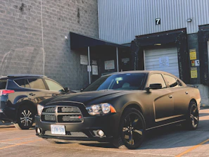Side profile of a Dodge Charger with sleek side skirts and fender flares against an industrial backdrop at dusk