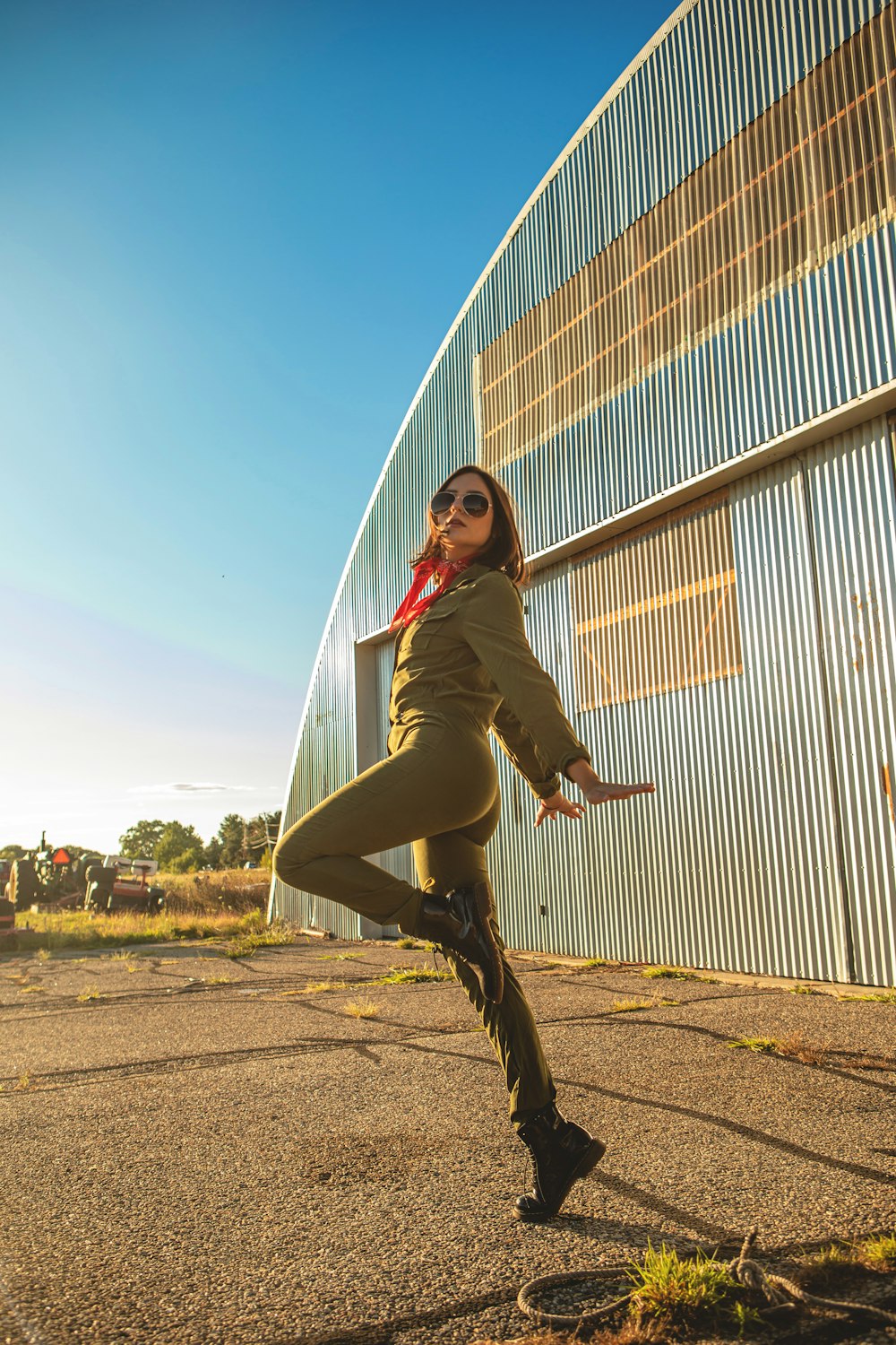 woman in green jacket and black pants jumping on brown field during daytime