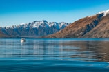 A close-up of a group enjoying a serene boat ride on a crystal-clear lake surrounded by mountains.