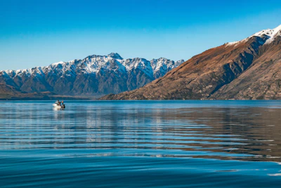 Family enjoying a boat ride on a crystal-clear lake surrounded by mountains