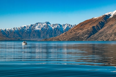 A close-up of a group enjoying a serene boat ride on a crystal-clear lake surrounded by mountains.