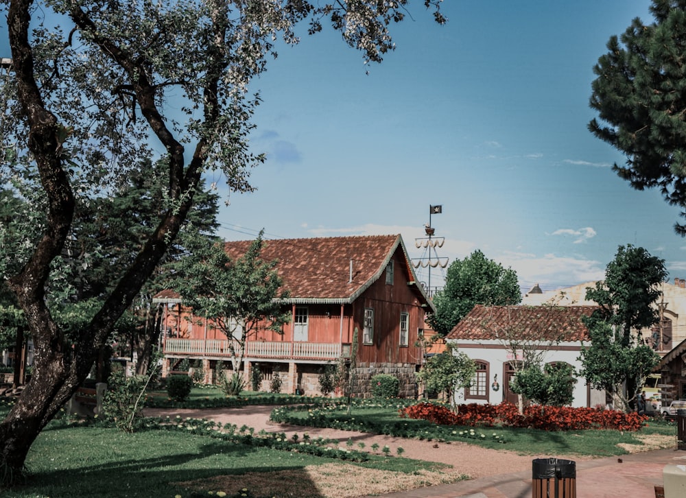 casa in cemento rosso e bianco vicino agli alberi verdi sotto il cielo blu durante il giorno