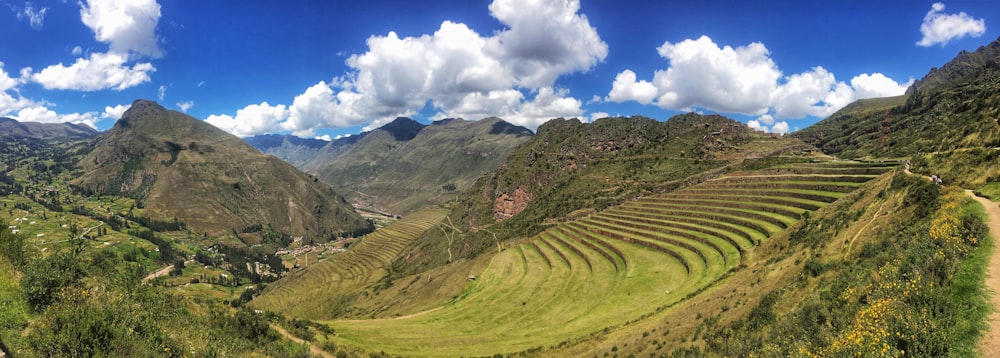 green grass field and mountain under blue sky during daytime