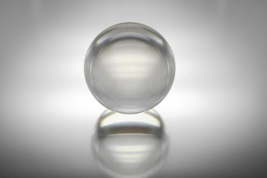 A clear glass sphere refracting light on a soft grey gradient