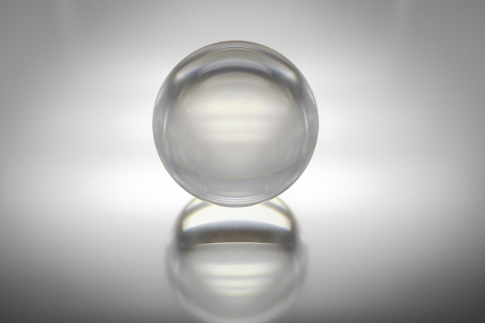 Boule de verre transparent sur surface blanche