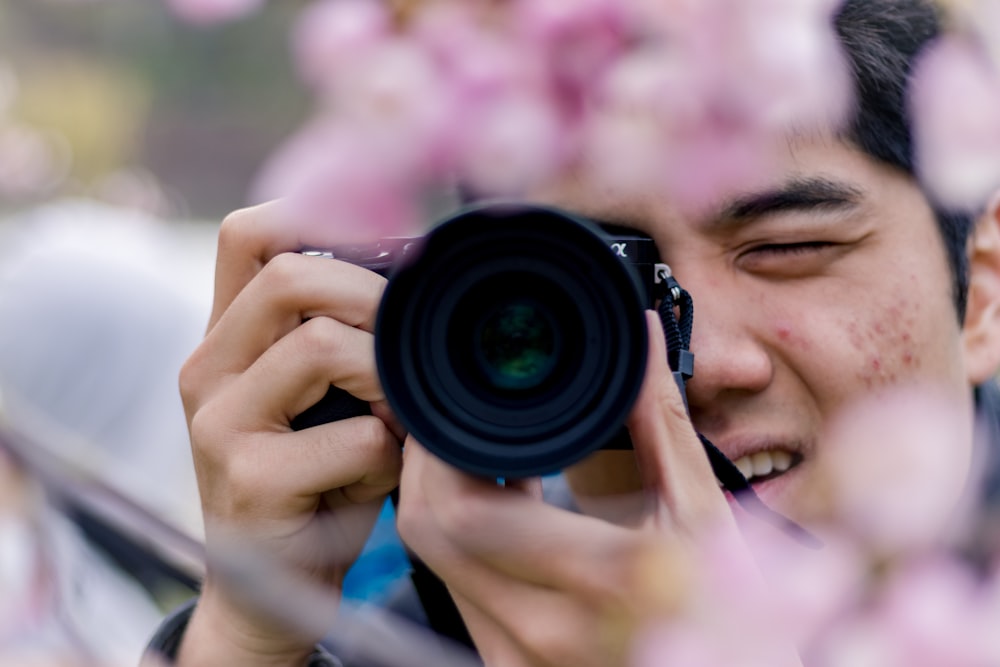 man in blue shirt holding black dslr camera