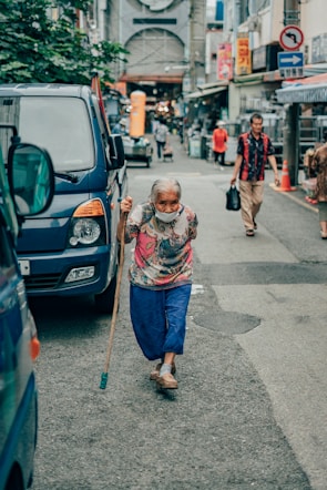 girl in white and red floral long sleeve shirt and blue denim jeans standing on sidewalk