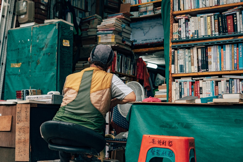 man in yellow long sleeve shirt sitting on chair reading book