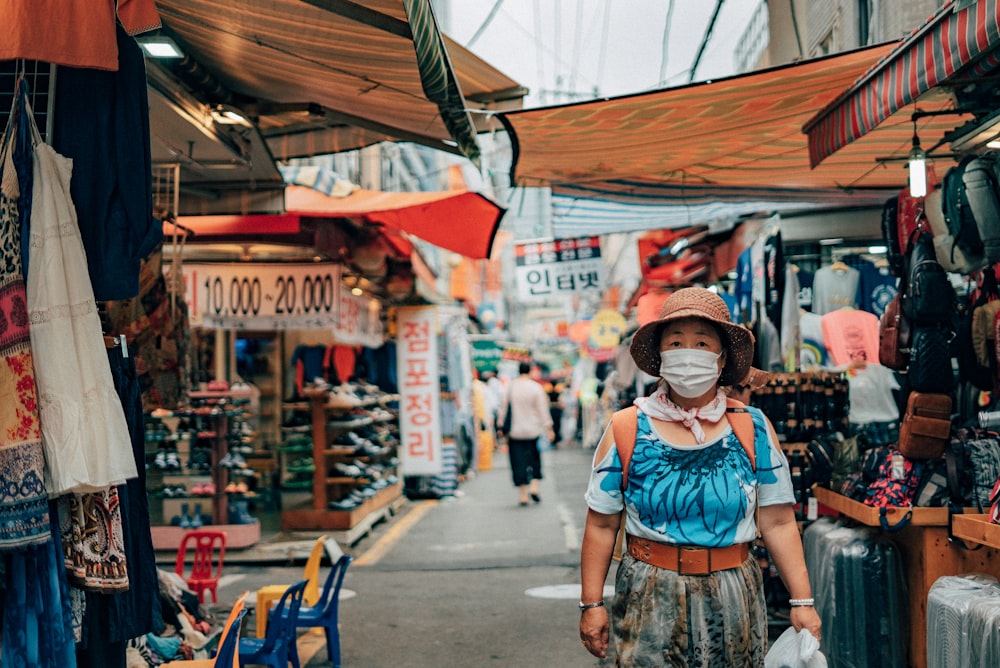 woman in blue and white floral dress wearing red hat standing on sidewalk during daytime