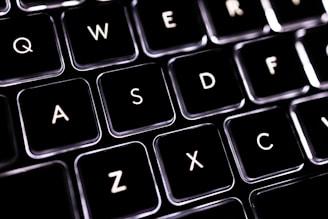 A close-up view of a computer keyboard highlighting the keys Q, W, E, R, A, S, D, F, Z, X, C. The lighting gives the keys a sleek and modern look, with a dark background that contrasts sharply with the illuminated letters.