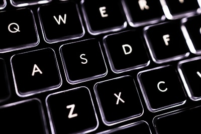 A close-up view of a computer keyboard highlighting the keys Q, W, E, R, A, S, D, F, Z, X, C. The lighting gives the keys a sleek and modern look, with a dark background that contrasts sharply with the illuminated letters.