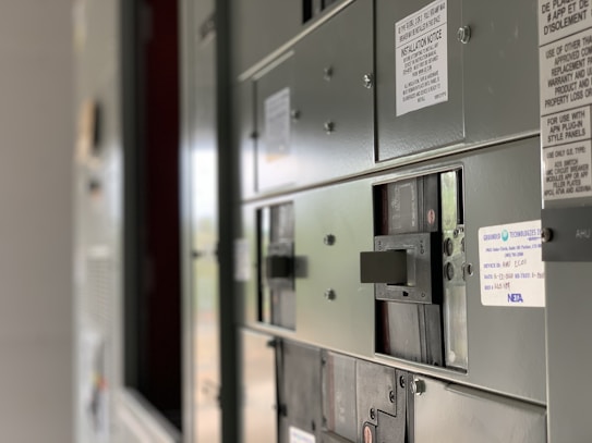 A close-up view of an industrial electrical panel with various switches and labels. The focus is on the switches, with the labels providing details about their use and installation instructions. The panel is metallic and has a utilitarian design.
