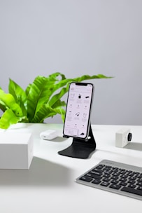 a cell phone sitting on a stand next to a keyboard