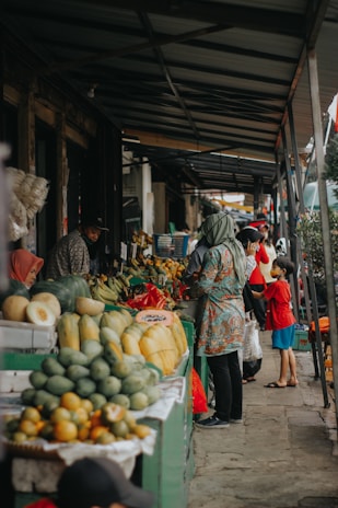 A group of travelers enjoying a local market filled with colorful fruits and crafts.