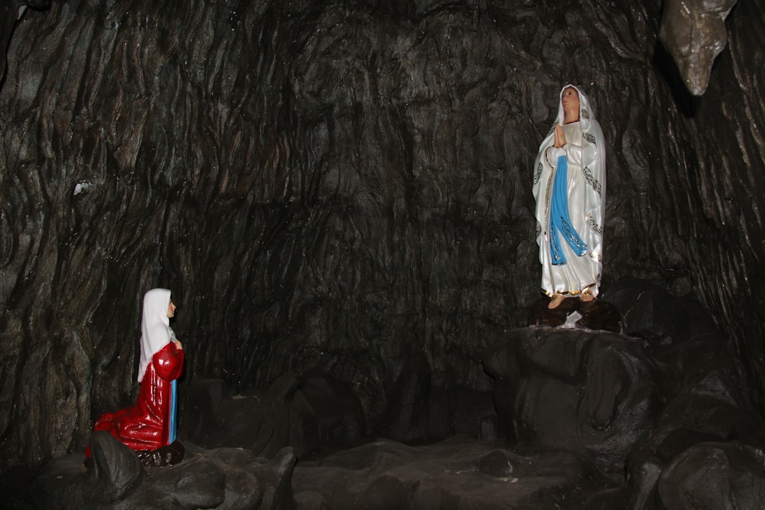 2 women standing on gray sand, Grotto