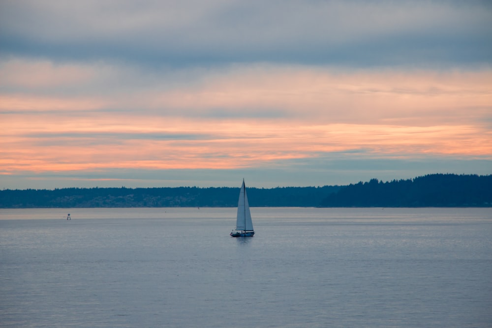 Weißes Segelboot auf See bei Sonnenuntergang