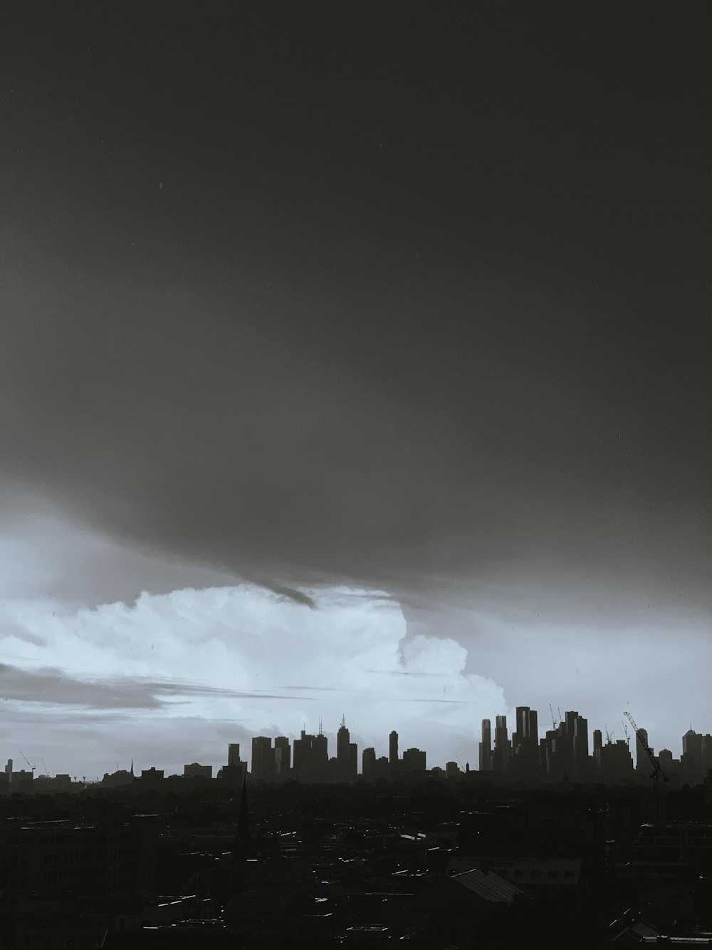 Graustufenfoto von Stadtgebäuden unter bewölktem Himmel