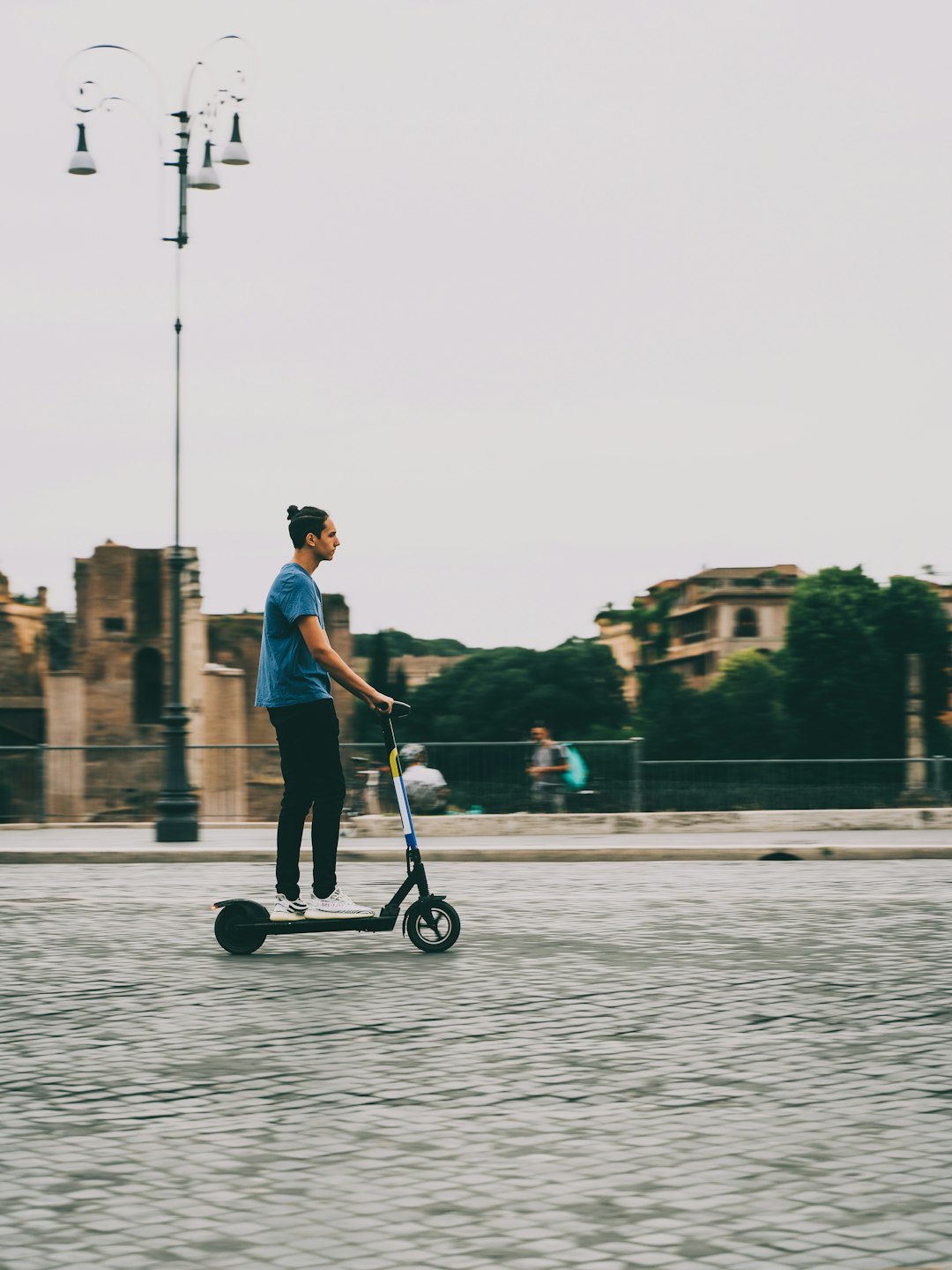 man in pink shirt and black pants riding kick scooter on water during daytime