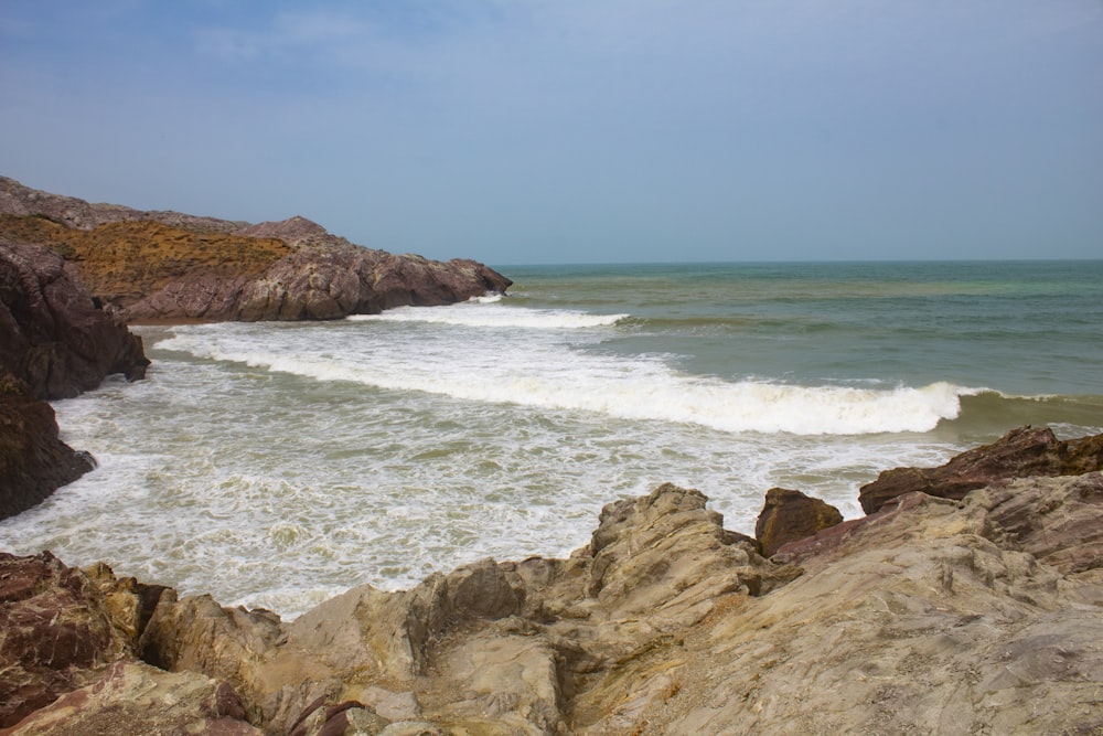 brown rocky shore near body of water during daytime