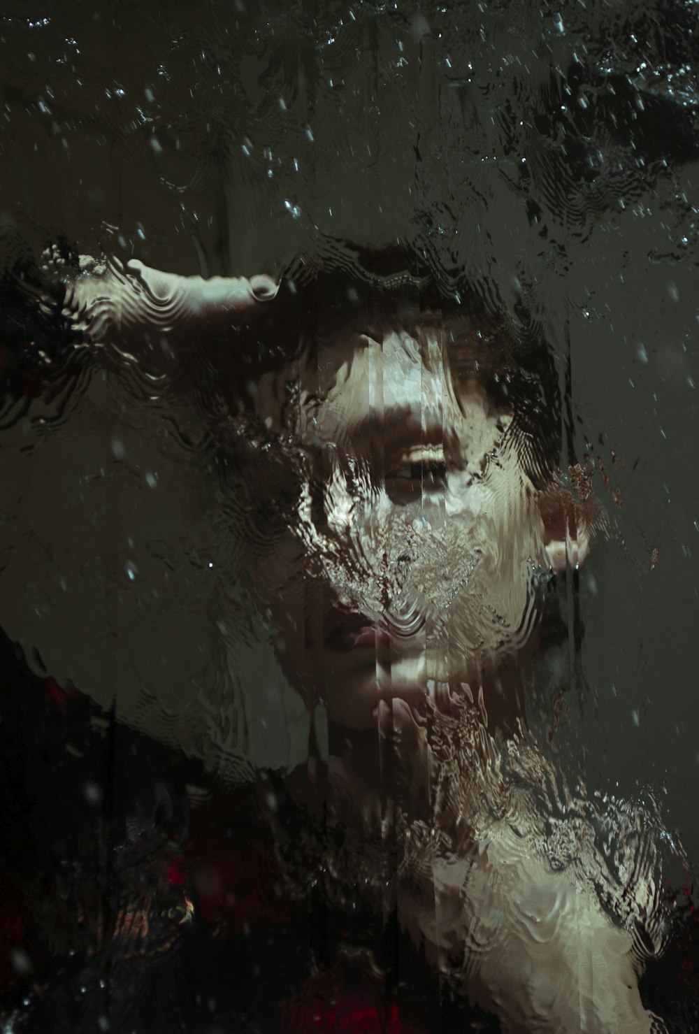 a woman's face is reflected in a wet window