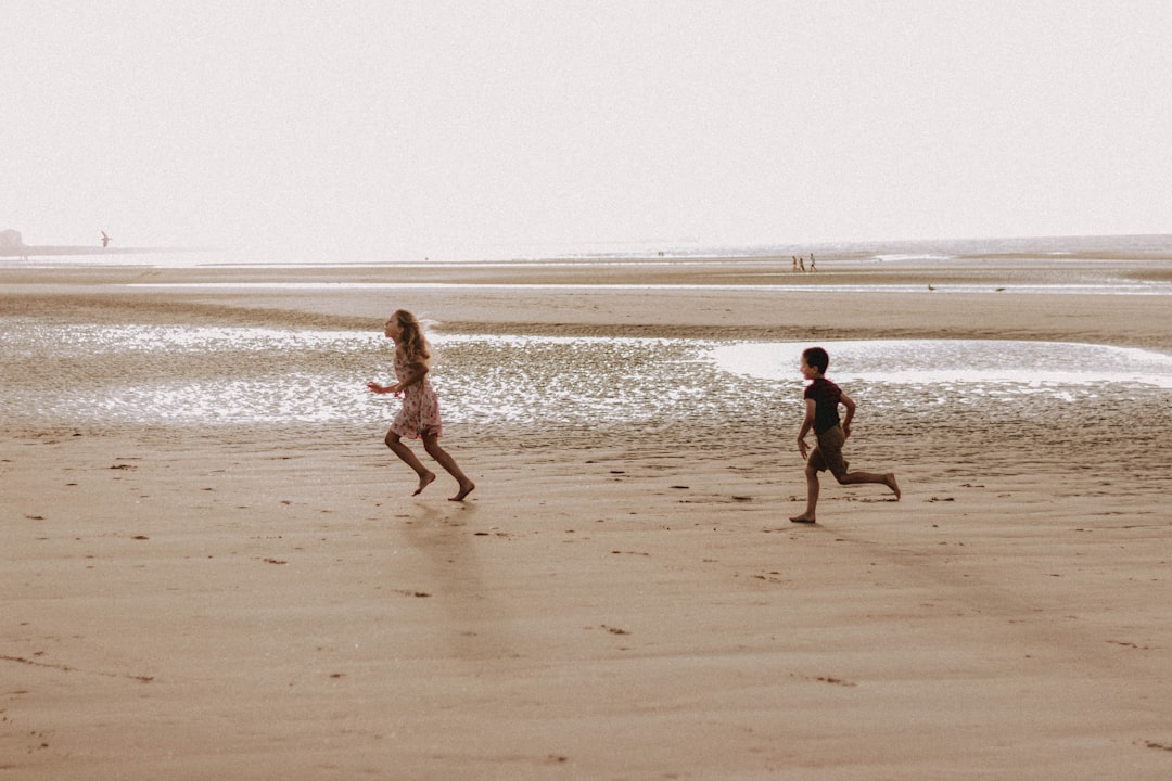2 boys running on beach during daytime