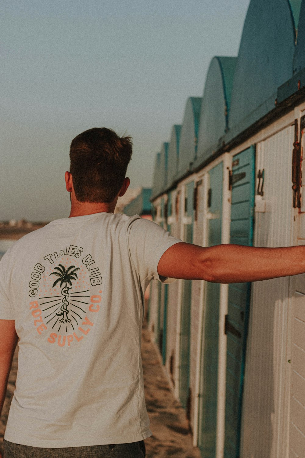 man in white crew neck t-shirt standing near green building during daytime