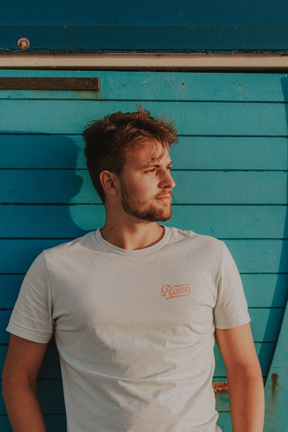 man in white crew neck t-shirt standing beside blue wall