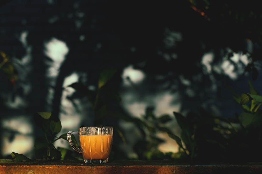 clear glass mug with brown liquid on brown wooden table