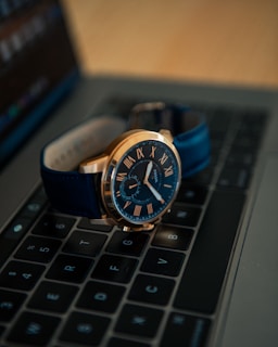 silver and black analog watch on black laptop computer