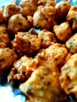 A close-up of crispy, golden pakoras with green chutney on the side.