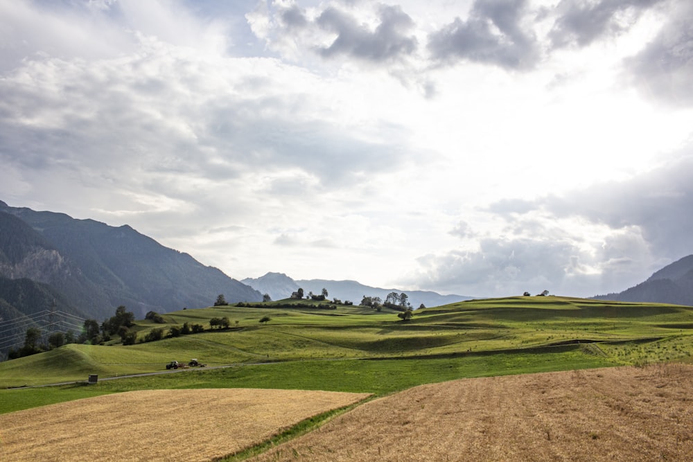 green grass field under cloudy sky during daytime