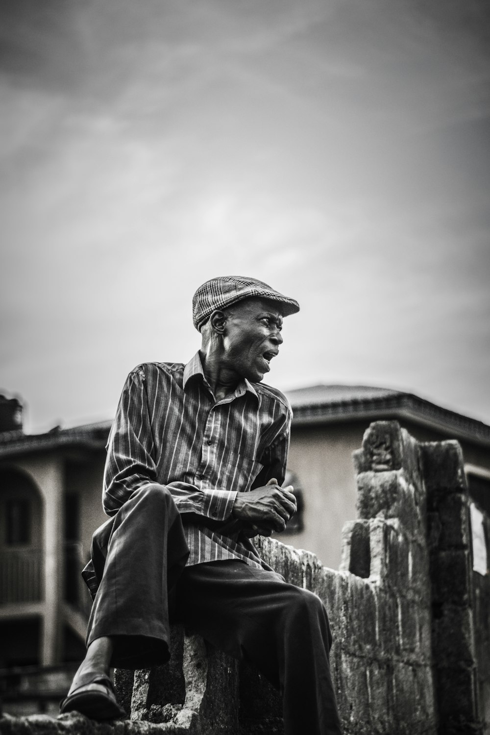 man in black and white stripe dress shirt and black pants sitting on concrete bench