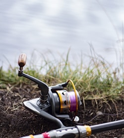 black and silver fishing reel on brown soil