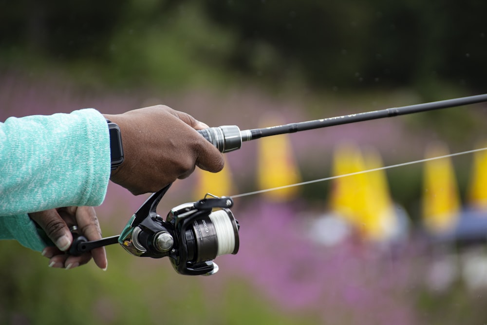 person holding black and silver fishing rod