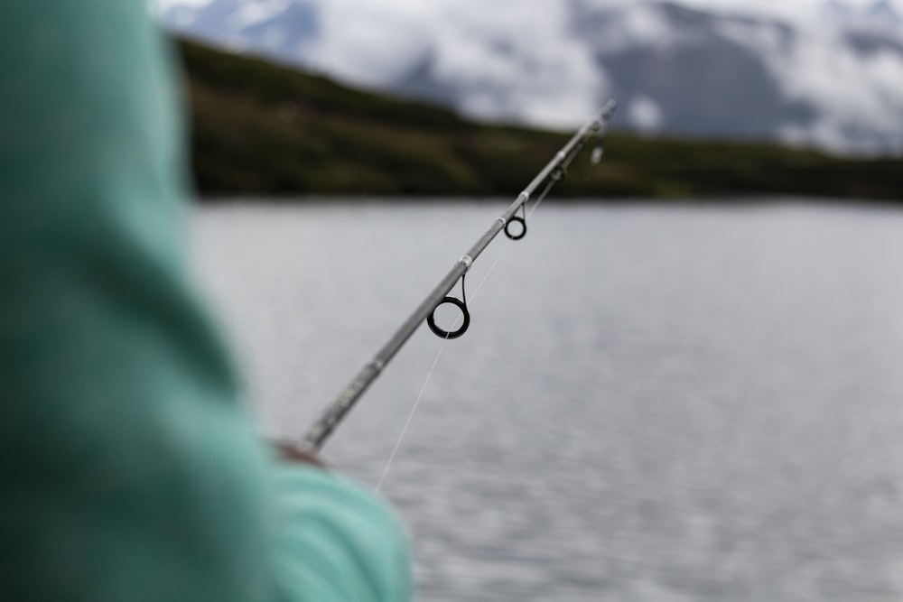 a person holding a fishing rod near a body of water