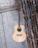 Close-up of a well-loved vintage guitar resting against a rustic wooden wall.