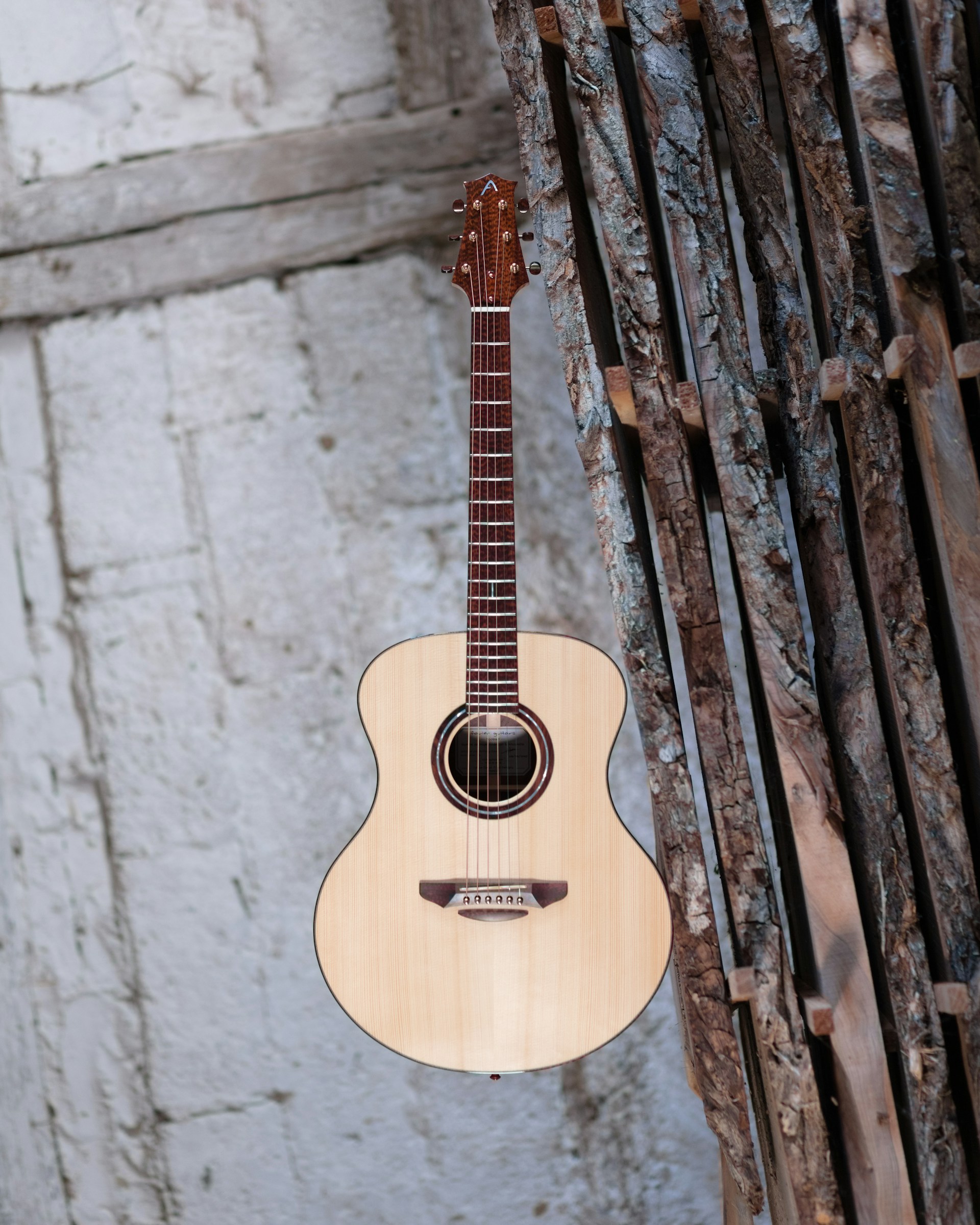 A close-up of handwritten lyrics and a guitar resting against a rustic wooden wall.