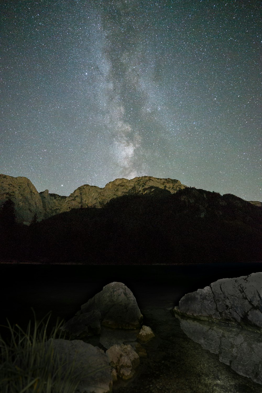 Specchio d'acqua vicino alla montagna sotto la notte stellata