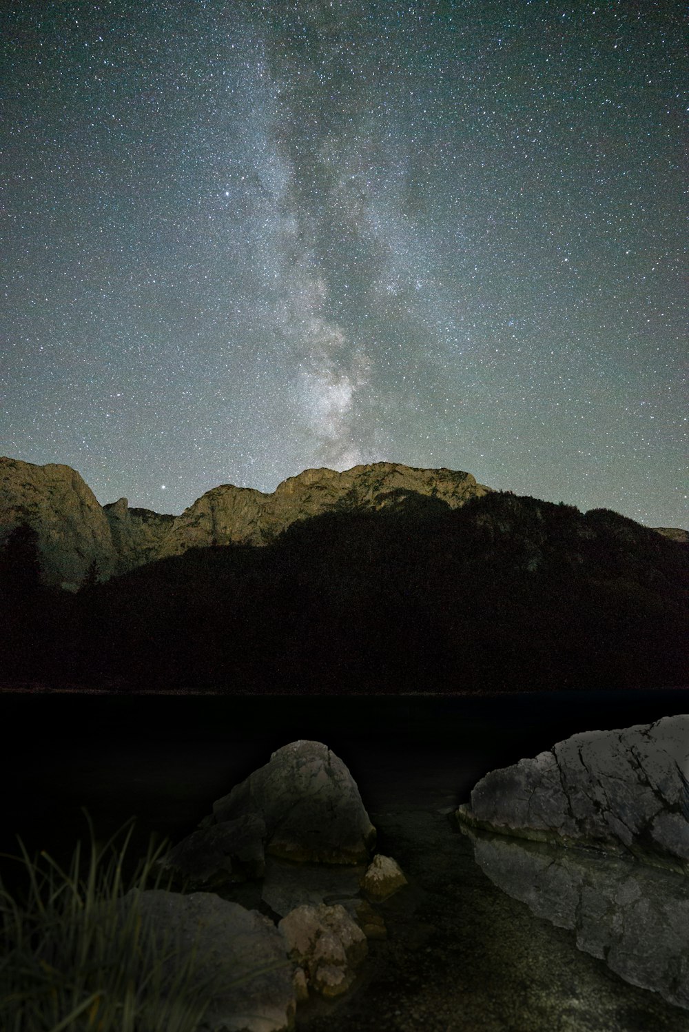 body of water near mountain under starry night